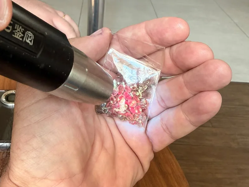 Inspeção de lote de alexandritas com caneta de luz antes da documentação